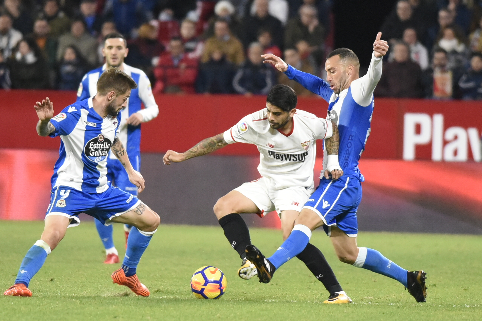 Banega disputa un balón ante dos rivales del Deportivo en Nervión