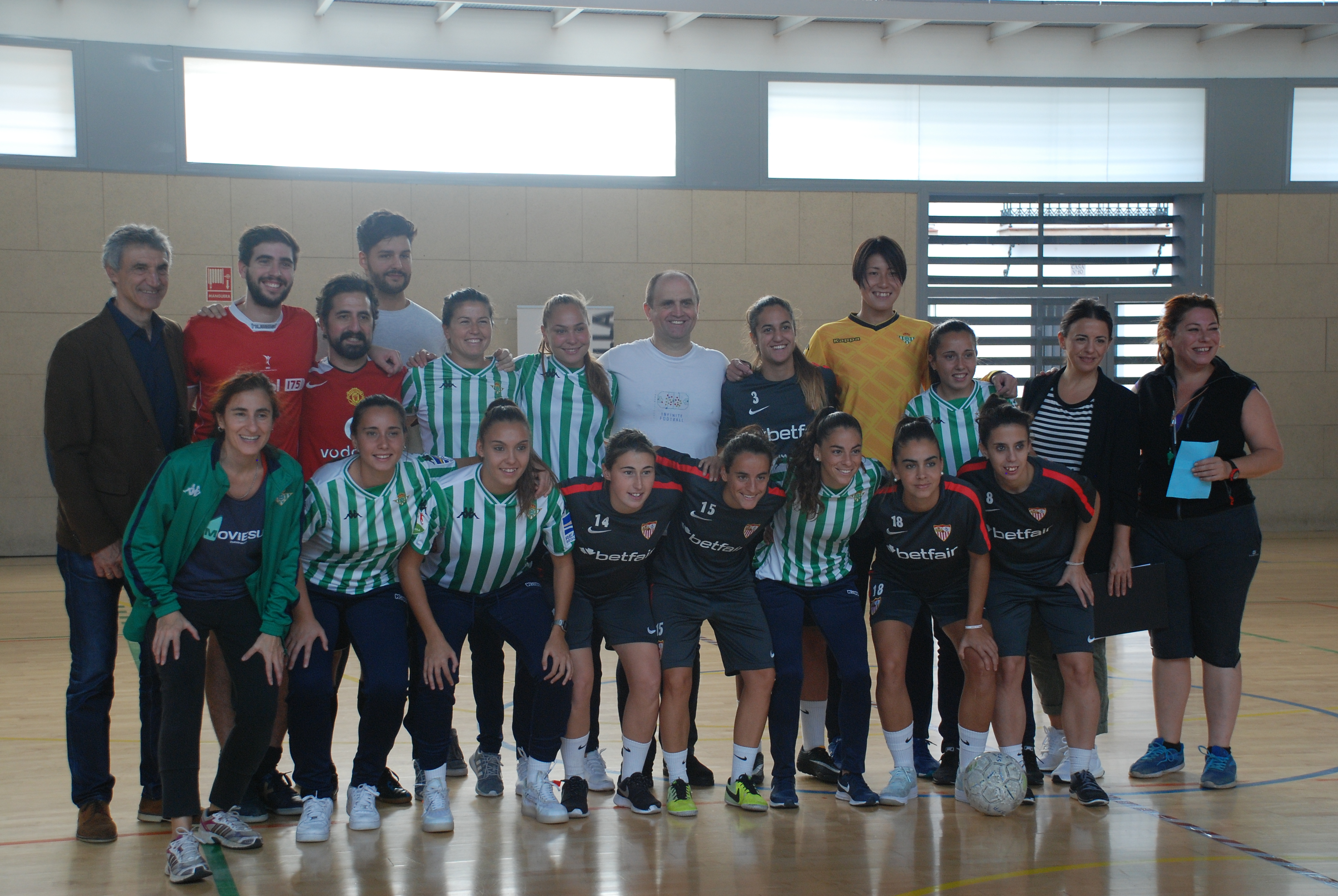Foto de familia de los participantes en el derbi femenino jugado con el equipo técnico de "La Peste" y la presidenta de la AAMMA además de las jugadoras del primer equipo femenino del Sevilla FC y Antonio Álvarez