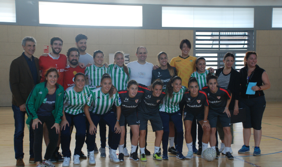 Foto de familia de los participantes en el derbi femenino jugado con el equipo técnico de "La Peste" y la presidenta de la AAMMA además de las jugadoras del primer equipo femenino del Sevilla FC y Antonio Álvarez