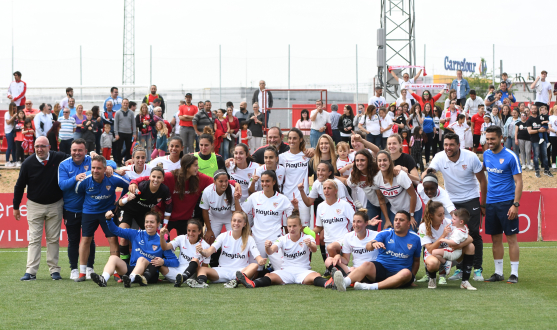El primer equipo femenino del Sevilla FC posa junto a los aficionados sobre el césped del campo 4 de la ciudad deportiva tras confirmar la permanencia en la Liga Iberdrola
